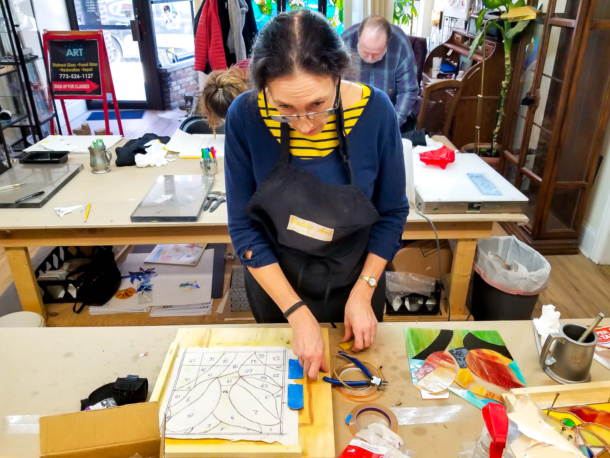 beginner student's hands soldering a small stained glass panel for the first time