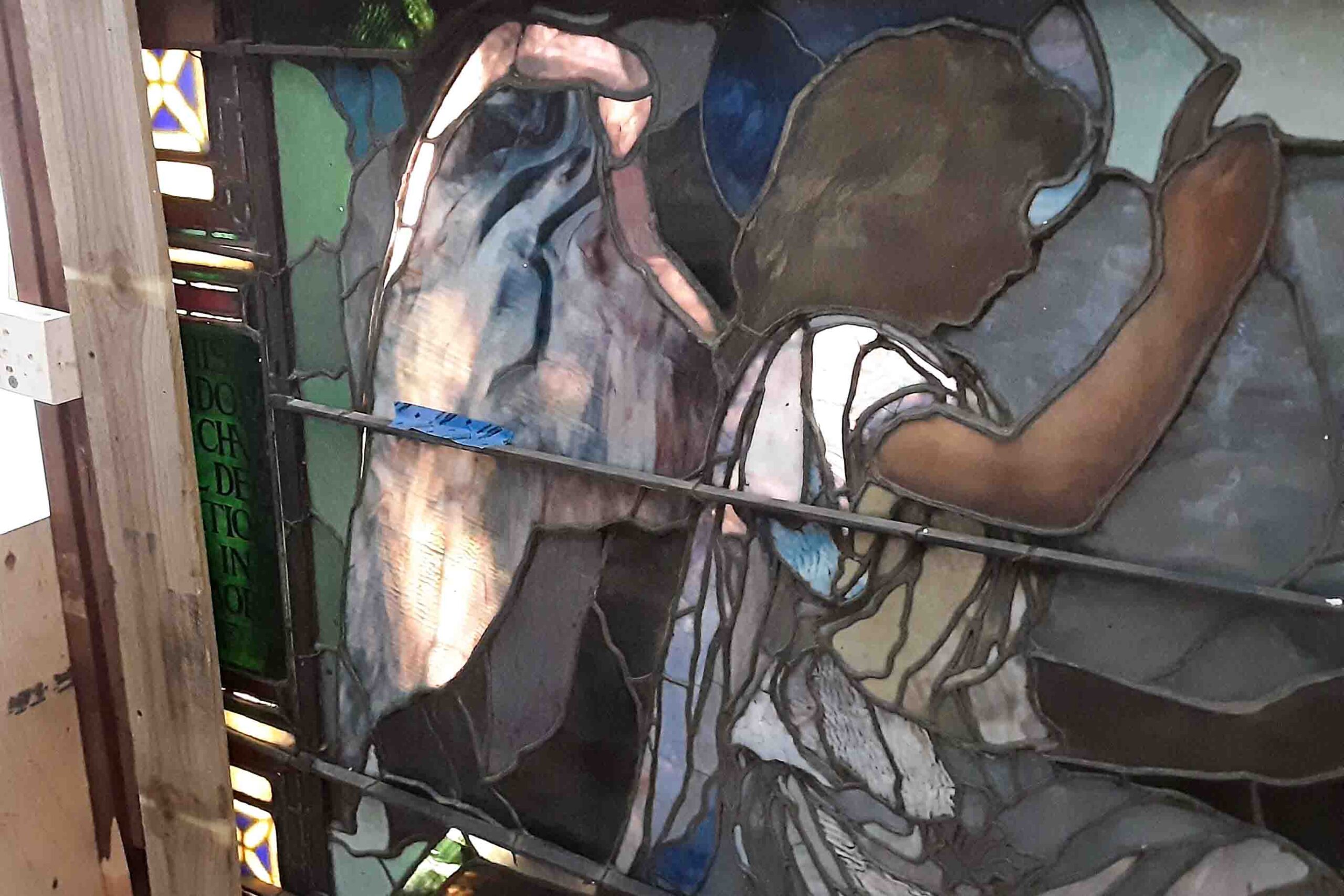 Conservator stabilizing cracked glass in John La Farge stained glass window