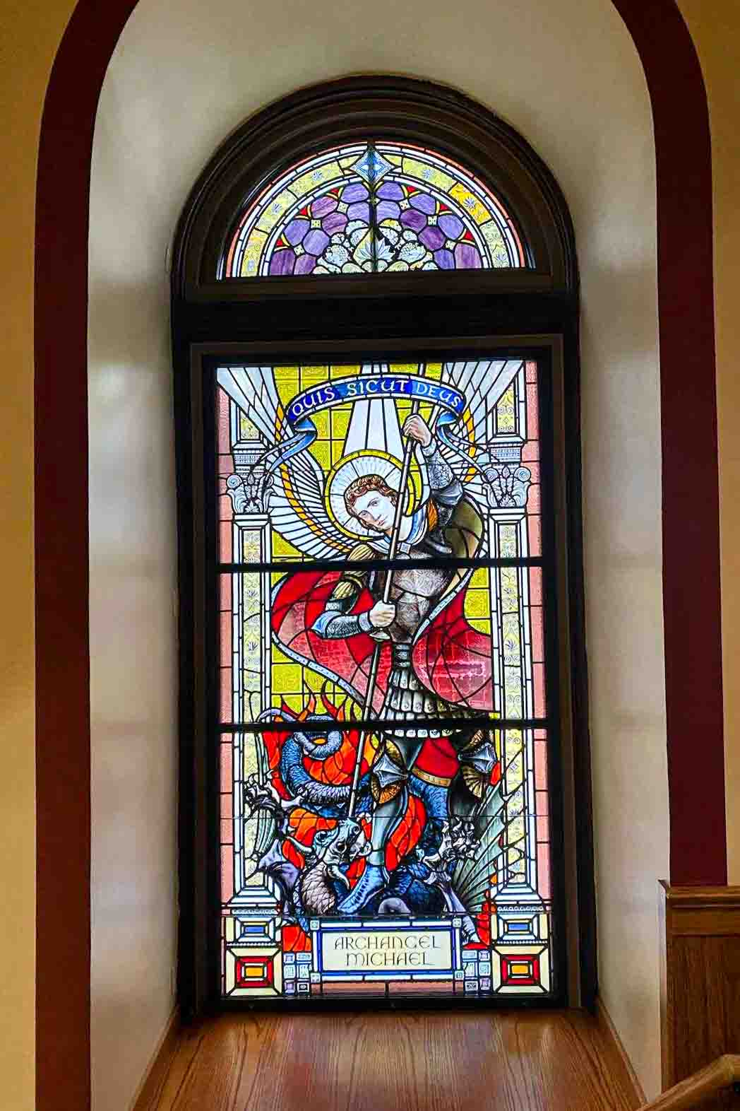 Stained glass artist Mindaugas Vitkauskas beside completed Archangel window at St. John Cantius Church